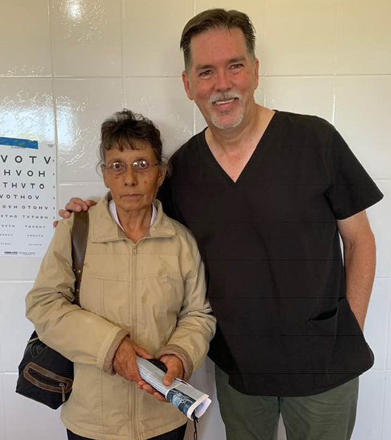 Bryan with a woman in Honduras wearing new eyeglasses, standing together inside a vision clinic.