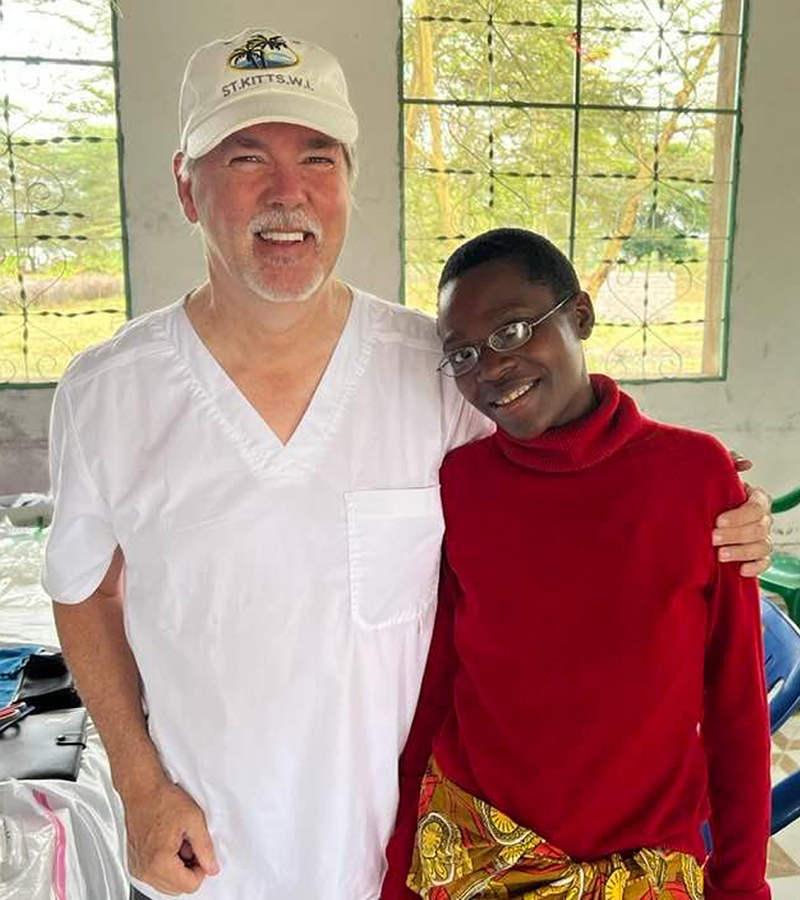 Bryan with a smiling young woman in Tanzania after receiving new eyeglasses.
